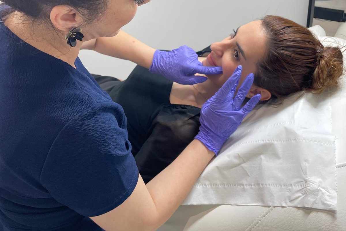 Practitioner gently checking a client’s lips at a dermal filler aftercare review — Bury clinic near Manchester
